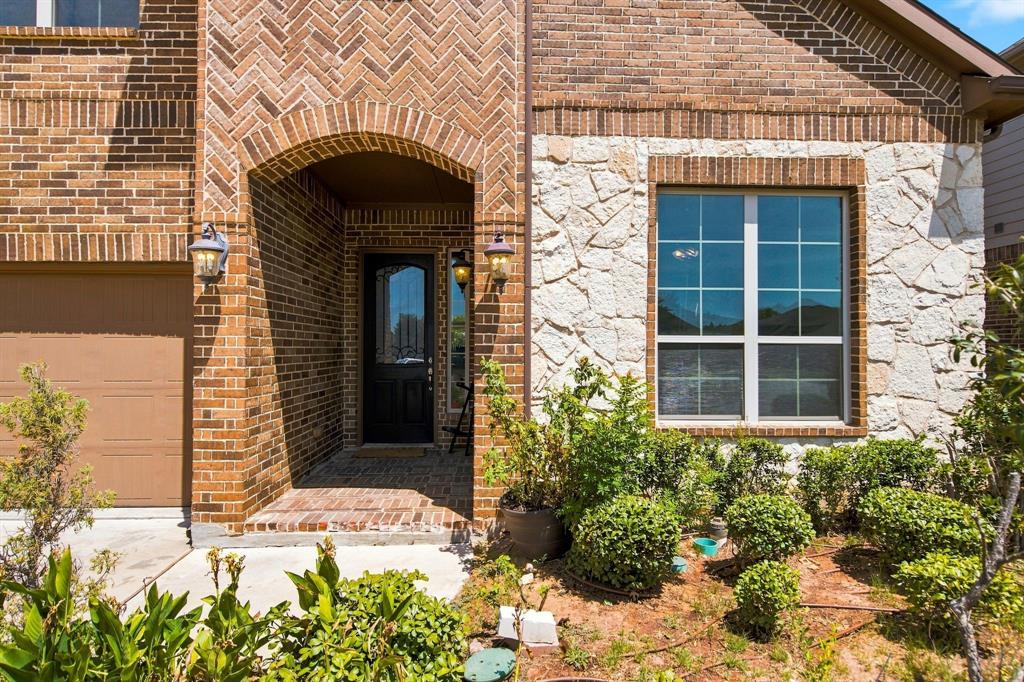 3908 Ranchman Boulevard Denton, TX 76210 - Photo 29 of 29 Brick exterior with herringbone accents, arched entryway, stone veneer detailing, and a garage door