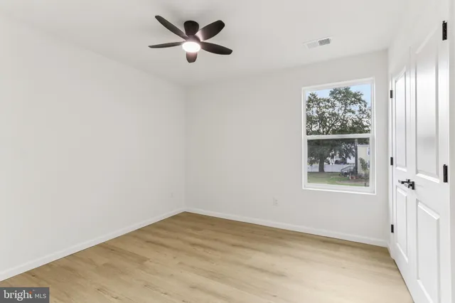 an empty room with ceiling fan and windows