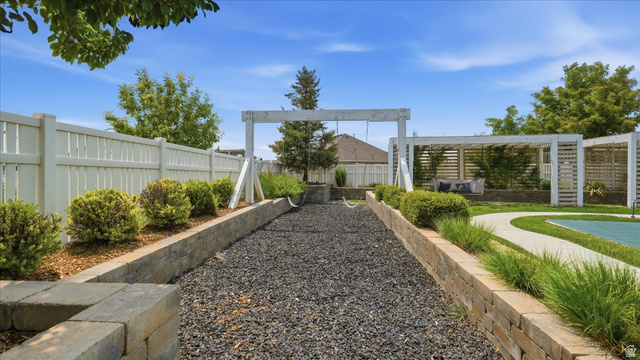 2038 East Ranch Road Eagle Mountain, UT 84005 - Photo 48 of 66 Expansive backyard featuring a gravel-filled activity area, a white picket fence, a swing structure, and a wood pergola with seating
