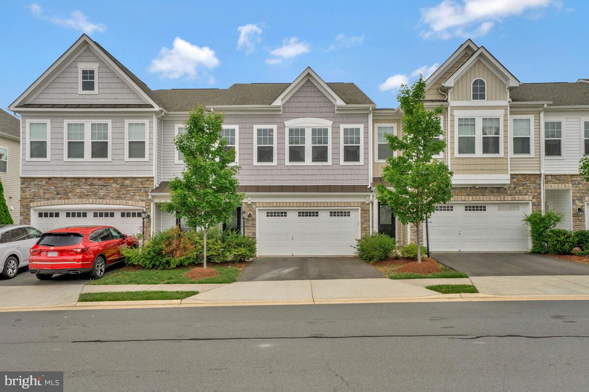 a front view of a house with a yard and car parked