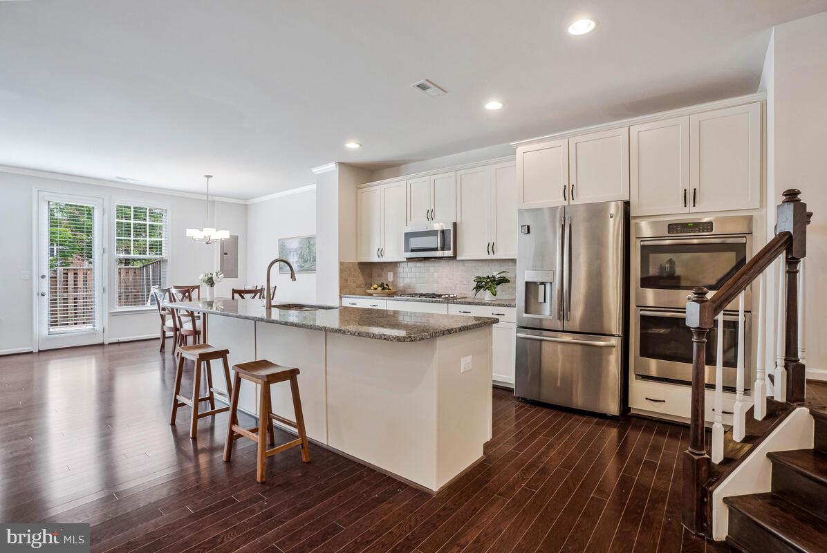 42523 Benfold Square Brambleton, VA 20148 - Photo 17 of 29 a kitchen with stainless steel appliances a refrigerator a stove a sink a dining table and chairs with wooden floor