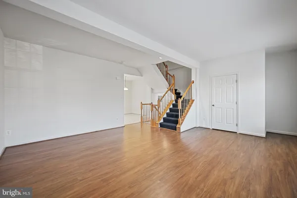a view of an empty room with wooden floor stairs and a ceiling fan