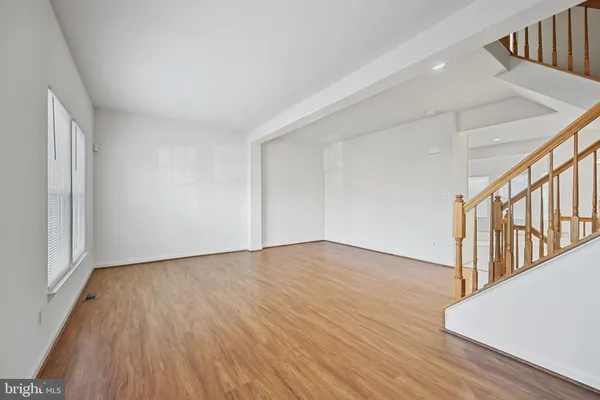 a view of an empty room with wooden floor and stairs