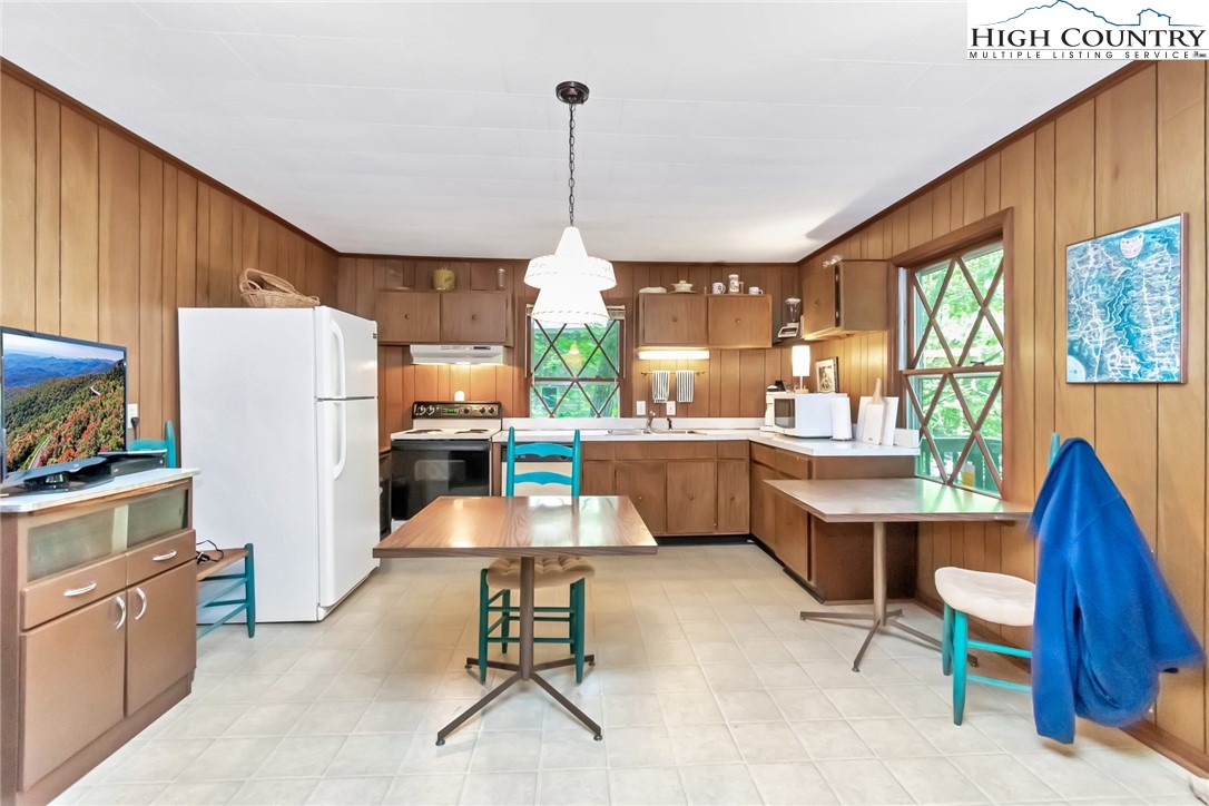 206 Oak Road Beech Mountain, NC 28604 - Photo 10 of 35 a kitchen with a refrigerator a stove top oven a sink dishwasher and a dining table with the kitchen view