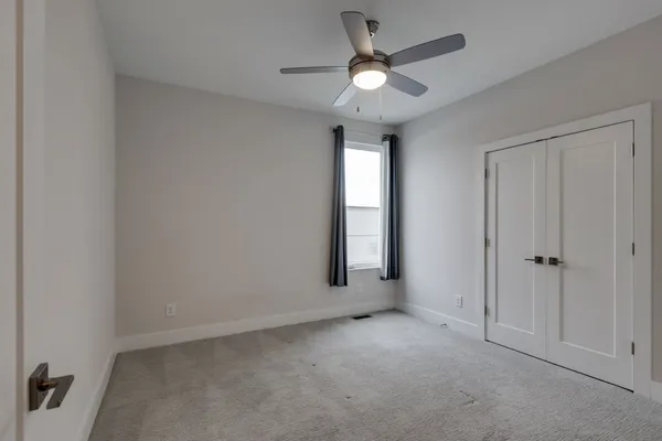 an empty room with windows and fan