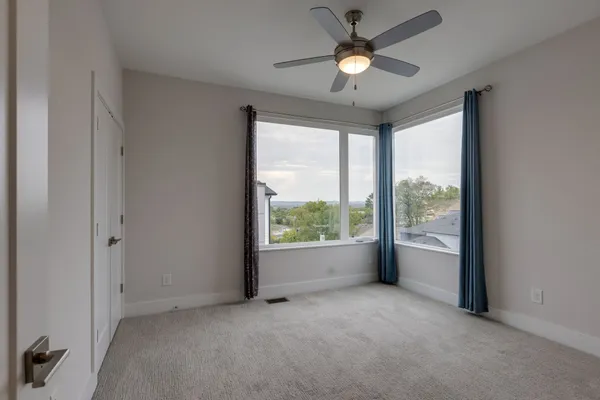 an empty room with windows and ceiling fan