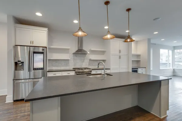 a kitchen with stainless steel appliances granite countertop a sink a refrigerator and a stove