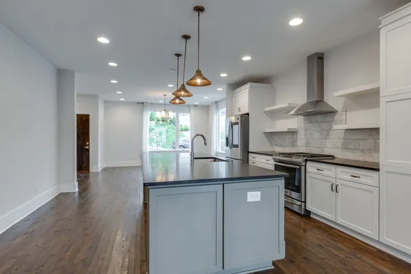 a kitchen with stainless steel appliances granite countertop a sink a stove and a wooden floors