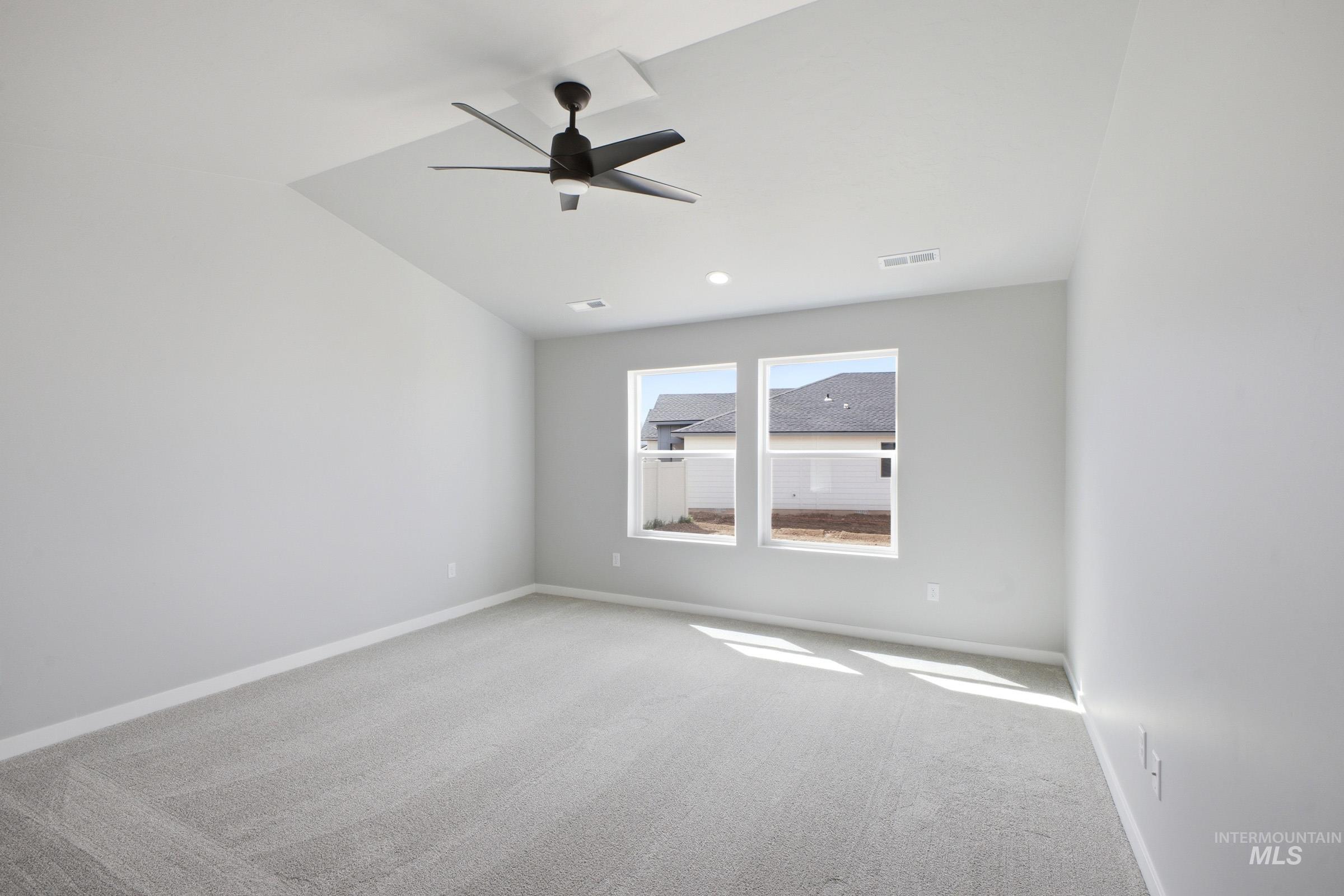 5315 South Memory Avenue Meridian, ID 83642 - Photo 19 of 24 Empty room featuring ceiling fan, vaulted ceiling, and light colored carpet