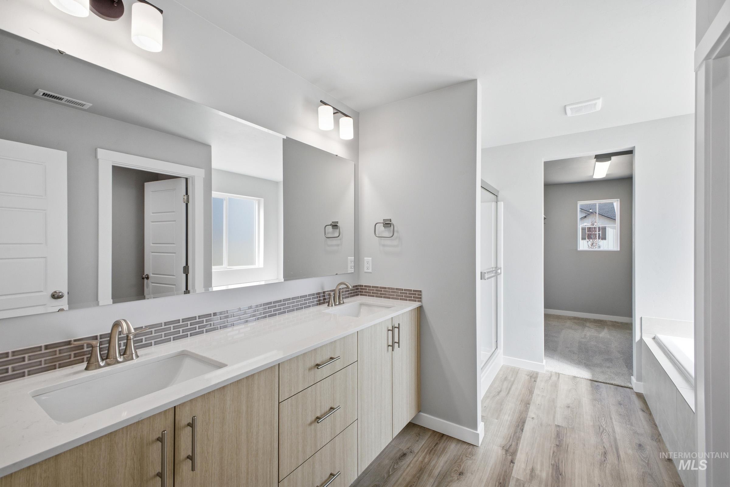 5315 South Memory Avenue Meridian, ID 83642 - Photo 21 of 24 Full bathroom with double vanity, a shower stall, light wood-type flooring, a garden tub, and backsplash