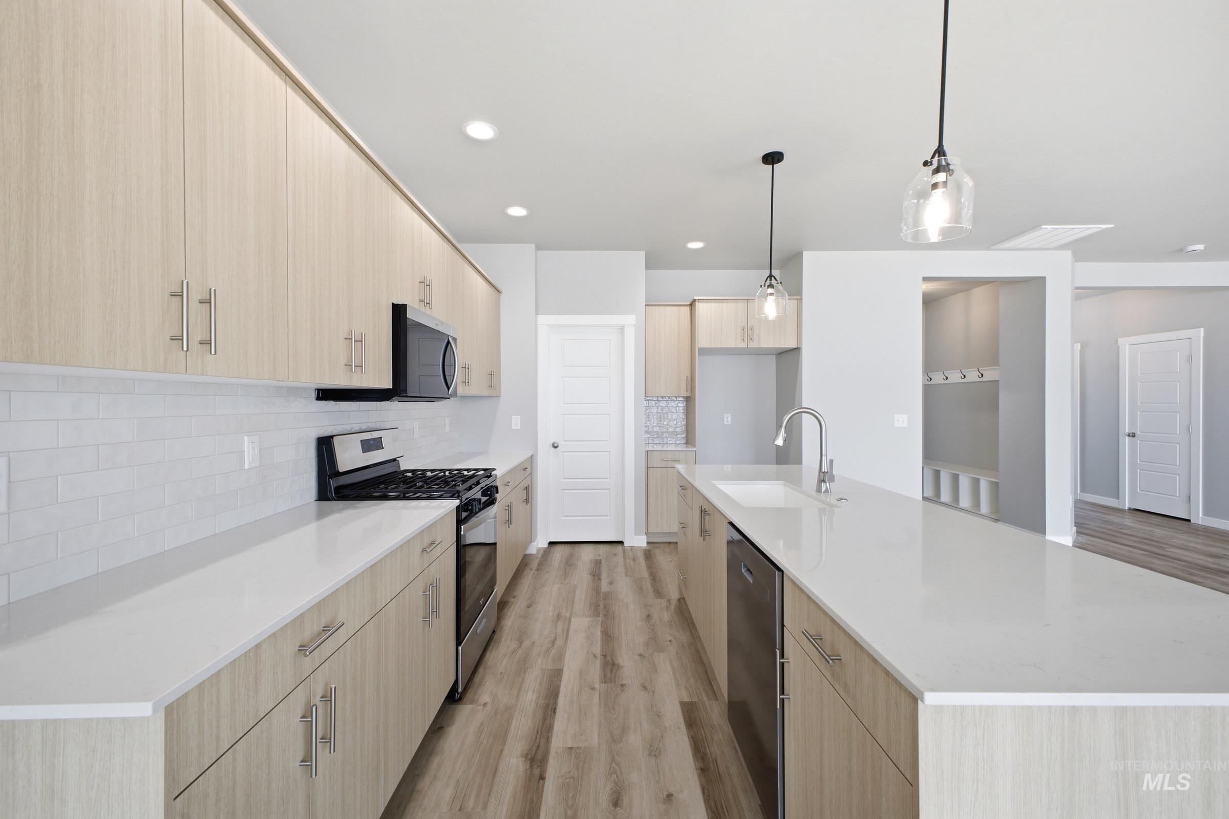 5315 South Memory Avenue Meridian, ID 83642 - Photo 5 of 24 Kitchen featuring light wood finish cabinetry, a kitchen island with sink, stainless steel appliances, light wood finished floors, and light stone countertops