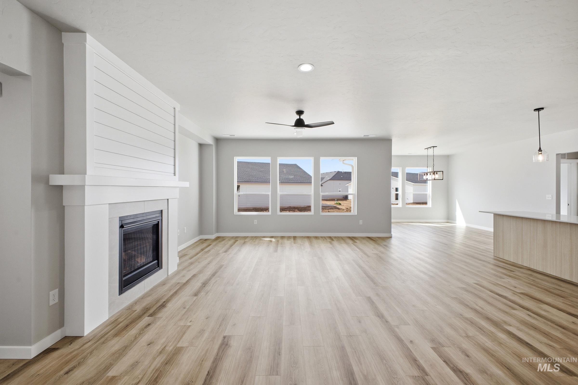 5315 South Memory Avenue Meridian, ID 83642 - Photo 7 of 24 Unfurnished living room featuring a ceiling fan, light wood-type flooring, and a large fireplace