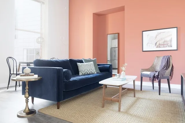 a living room with furniture a large window and a painting on the wall