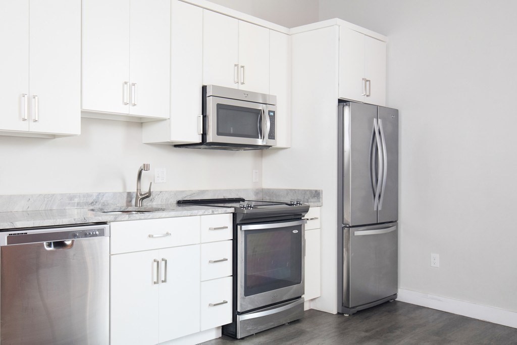 630 Washington Street, Unit 305 Boston, MA 02111 - Photo 4 of 9 a kitchen with stainless steel appliances granite countertop white cabinets a refrigerator and a stove top oven
