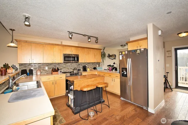 a kitchen with kitchen island granite countertop a sink a stove and a refrigerator
