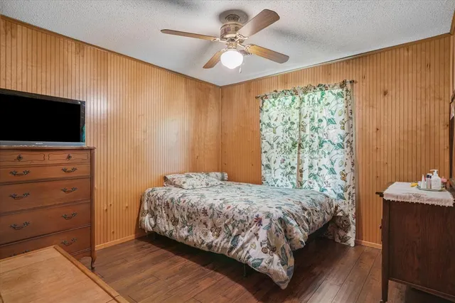 a bedroom with a bed a flat screen tv and a chandelier