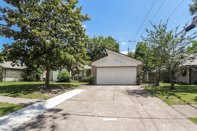 a view of a house with a yard and large tree