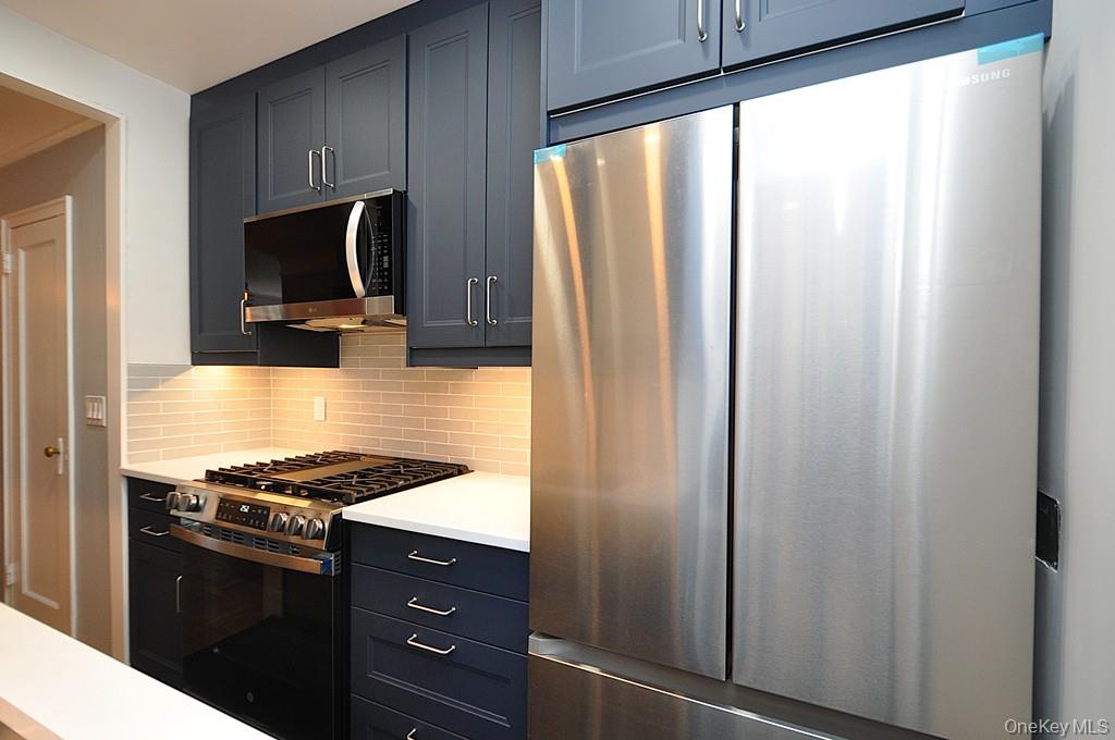 196 Garth Road, Unit 1G Scarsdale, NY 10583 - Photo 12 of 35 a kitchen with stainless steel appliances a refrigerator stove and microwave