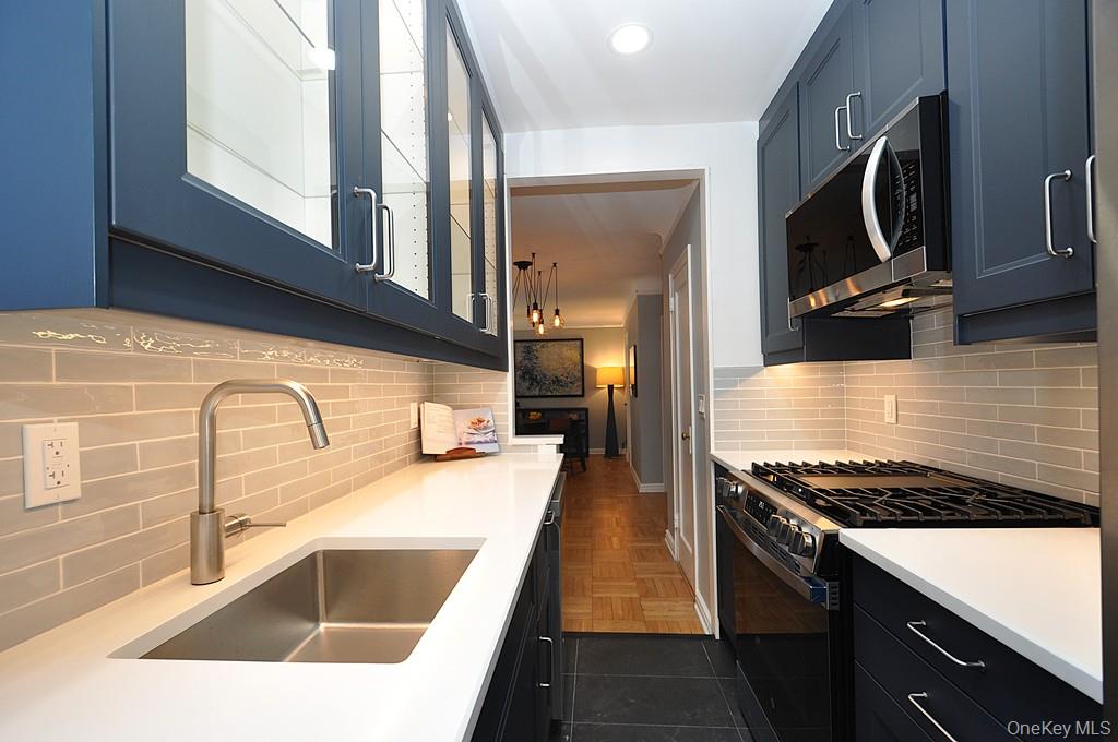 196 Garth Road, Unit 1G Scarsdale, NY 10583 - Photo 15 of 35 a kitchen with stainless steel appliances granite countertop a sink and a stove top oven with wooden floor
