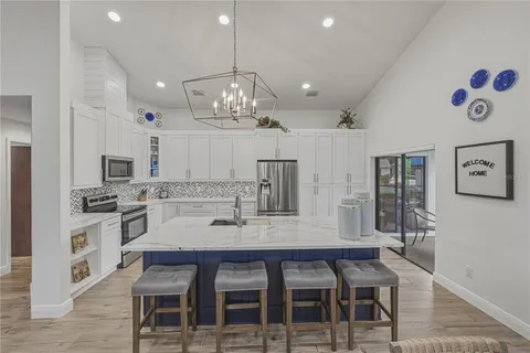 a kitchen with granite countertop a refrigerator a sink and white cabinets