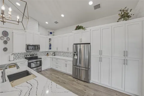 a living room with stainless steel appliances furniture a rug and a kitchen view