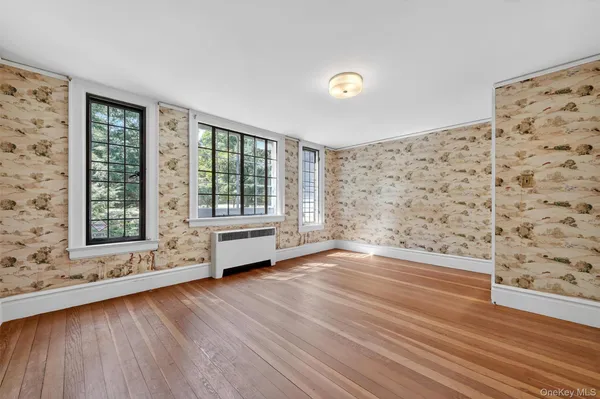 a view of an empty room with a window and wooden floor