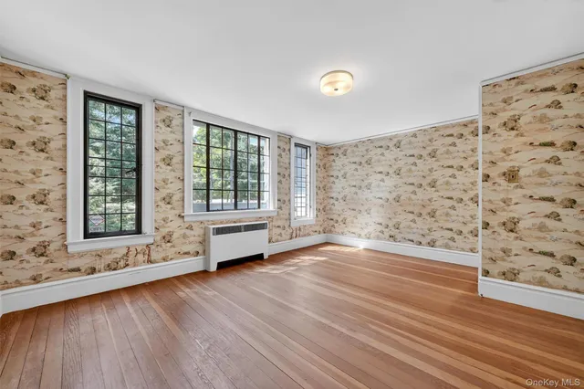 a view of an empty room with a window and wooden floor