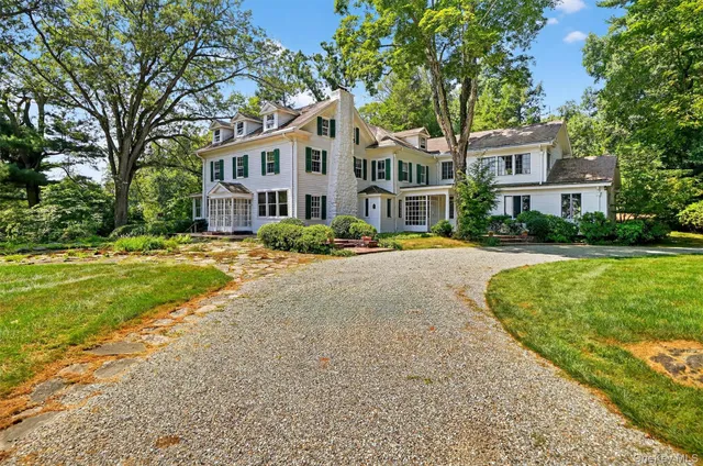 a front view of a building with a garden and trees