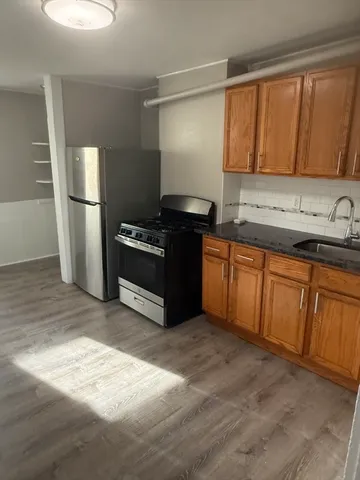 a kitchen with sink a refrigerator and wooden cabinets