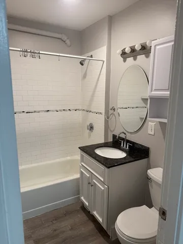 a bathroom with a granite countertop sink mirror toilet and bathtub
