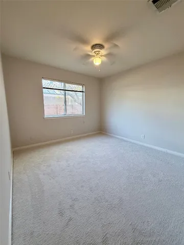 an empty room with a window and a fan