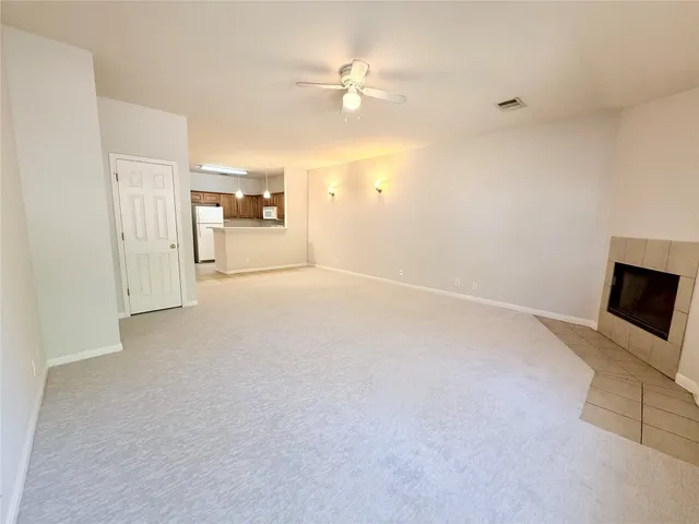 a view of a livingroom with a fireplace a ceiling fan and a window