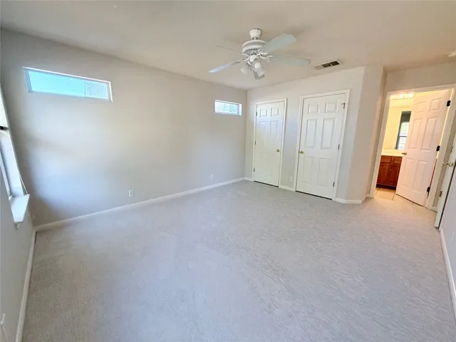 an empty room with windows and chandelier fan