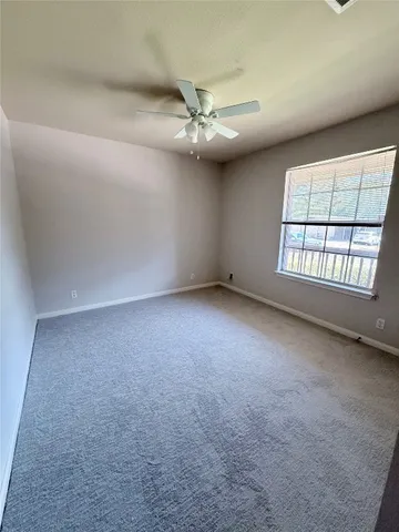 an empty room with windows and ceiling fan