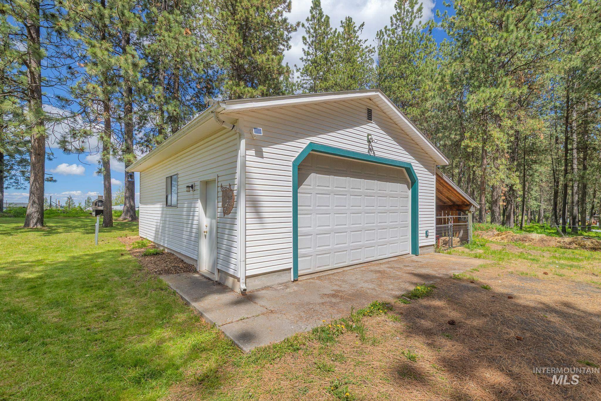 1820 Winchester Road Winchester, ID 83555 - Photo 29 of 50 Detached garage featuring white vinyl siding, a paneled garage door, and a covered lean-to structure