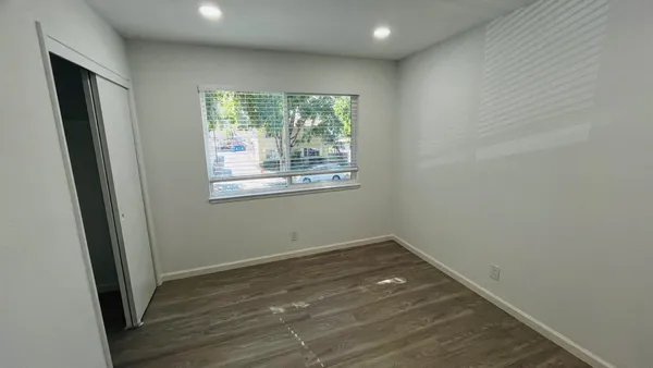 an empty room with wooden floor and windows