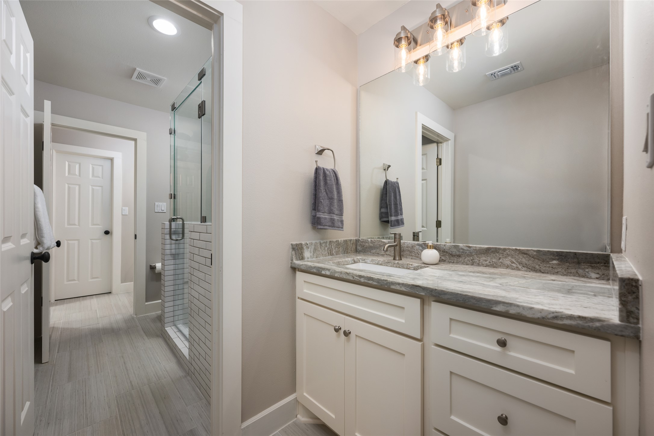 1276 Canyon Crossing View Dripping Springs, TX 78620 - Photo 20 of 33 a bathroom with a granite countertop sink a mirror and a shower