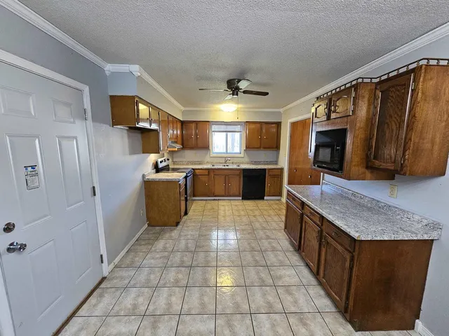 a large kitchen with stainless steel appliances granite countertop a stove top oven a sink dishwasher and a refrigerator