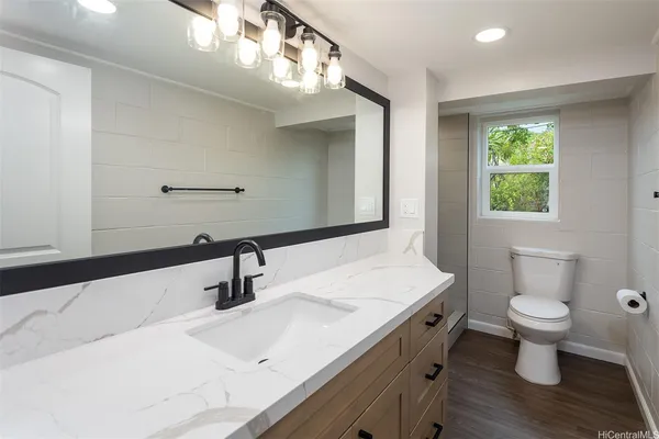 a bathroom with a sink a toilet a mirror and window