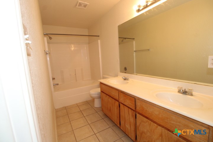 305 Cedar Ridge Drive, Unit B Nolanville, TX 76559 - Photo 12 of 14 a bathroom with a granite countertop sink a toilet and shower