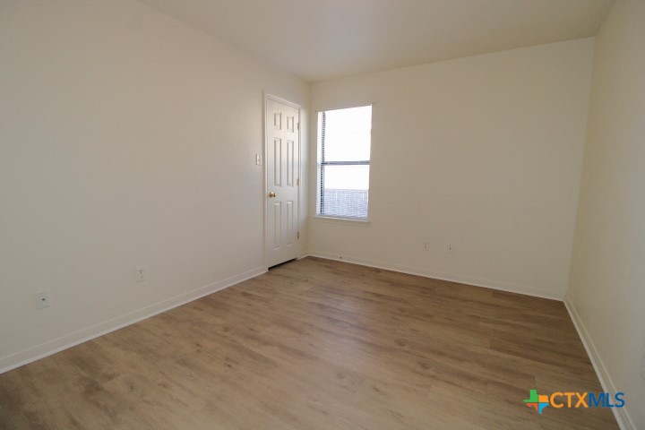 305 Cedar Ridge Drive, Unit B Nolanville, TX 76559 - Photo 13 of 14 an empty room with wooden floor and windows