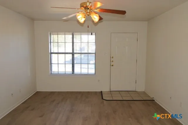 an empty room with windows and fan