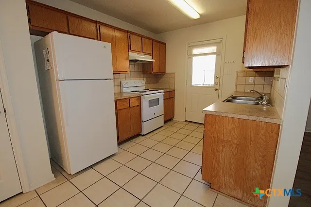 a kitchen with a refrigerator sink stove and cabinets