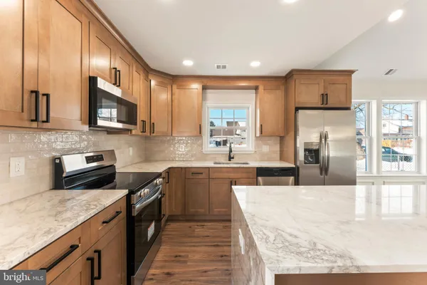 a kitchen with stainless steel appliances granite countertop wooden cabinets a stove top oven a sink and dishwasher