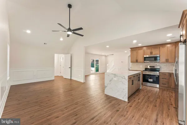 a living room with stainless steel appliances kitchen island hardwood floor and a view of kitchen