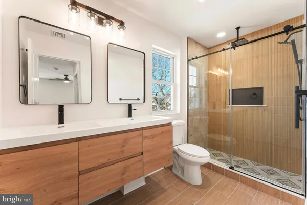 a bathroom with a granite countertop bathtub shower sink vanity and toilet