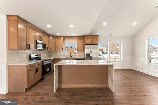 a large kitchen with stainless steel appliances granite countertop a stove a sink dishwasher and a microwave oven with wooden floor