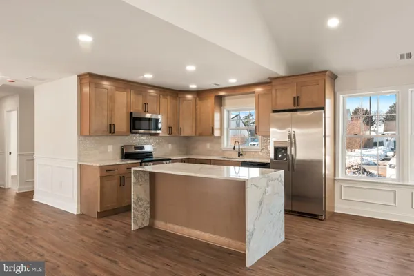 a kitchen with stainless steel appliances granite countertop a refrigerator a stove a sink and a microwave