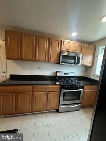 a kitchen with granite countertop a stove top oven cabinetry a sink and a window
