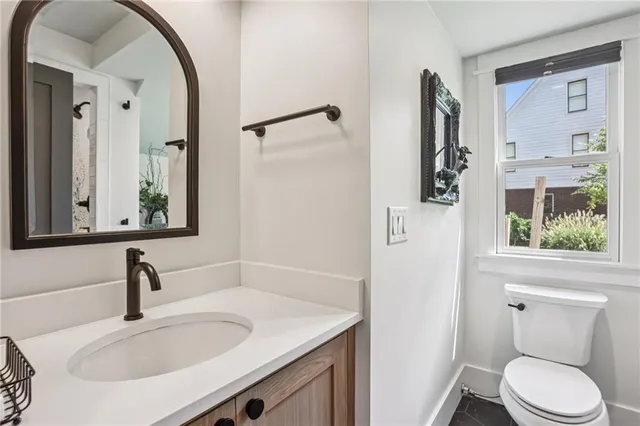 a bathroom with a granite countertop sink toilet and a mirror